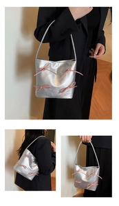 Detail of silver metallic tote bag featuring four pink ballet-style ribbon bows on the front