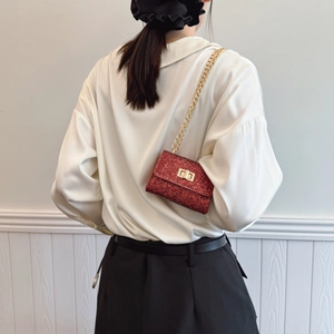 Mini red rhinestone crossbody bag with gold chain strap shown on model's outfit