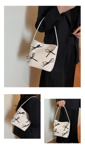Detail of white bucket bag featuring elegant black bow decorations and smooth PU texture