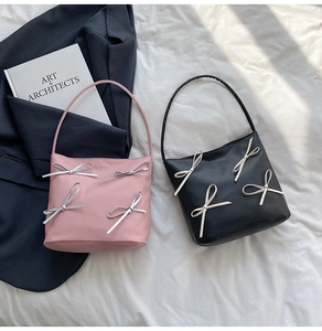 Close-up of pink and black bow shoulder bags on aesthetic fabric and blazer background