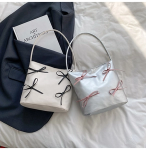Chic bucket bags in beige with black bows and silver with pink bows on a soft backdrop