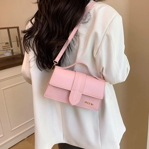 Rosa minimalistische Crossbody-Handtasche mit Tragegriff und Goldlogo am Model