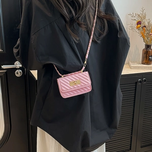 Mini pink quilted crossbody bag with chain strap and gold hardware shown on model