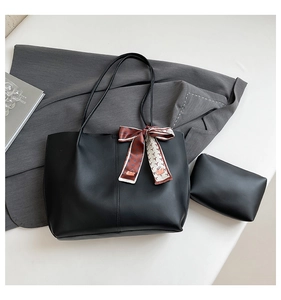 Detail of black leather tote bag with a small pouch and decorative silk scarf on the side