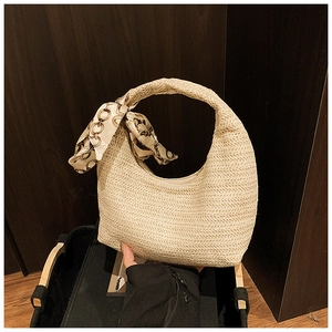 Detail der handgewebten Strohtasche mit Seidenschal-Dekor am Griff im Urlaubsstil