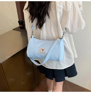 Detail view of a light blue canvas barrel bag with cartoon dog patch shown on model