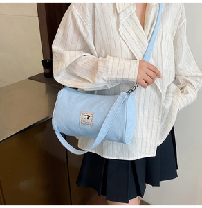 Detail of light blue canvas cylinder bag with dog illustration and wide strap on model