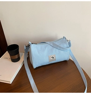Detail of light blue denim pillow bag with cute cartoon dog embroidery on a wooden table