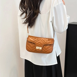 Brown quilted crossbody bag with gold turn-lock and chain strap on a model