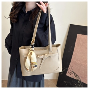 Détail d'un sac cabas en cuir beige avec boucle dorée et foulard en soie sur la poignée