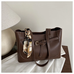 Détail du cabas en cuir marron foncé avec coutures blanches et foulard en soie imprimé