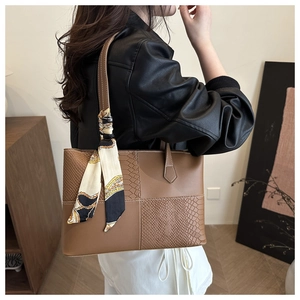 Detail of brown tote bag featuring mixed textures and decorative geometric printed silk scarf