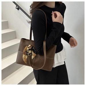 Macro detail of brown tote bag featuring faux crocodile texture and printed silk scarf wrap