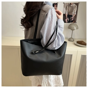 Vue détaillée du grand sac cabas noir à l'épaule montrant la texture du cuir mat minimaliste