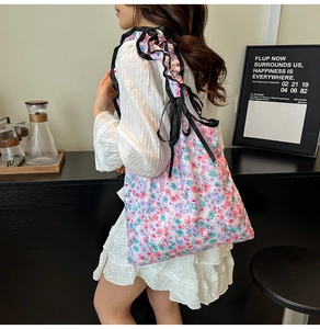 Dettaglio borsa shopper floreale con spalline in rete nera e fiocco decorativo