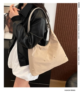 Detail of beige hobo bag featuring gold studs and spacious design on a female model