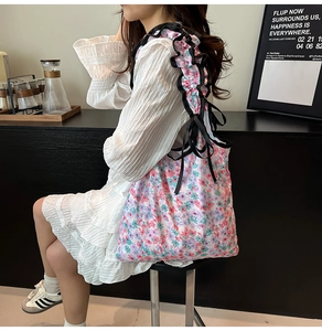 Dettaglio della borsa tote floreale con tracolla a volant nera e fiocco decorativo