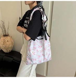 Borsa tote floreale con tracolla a volant e fiocco indossata lateralmente dalla modella