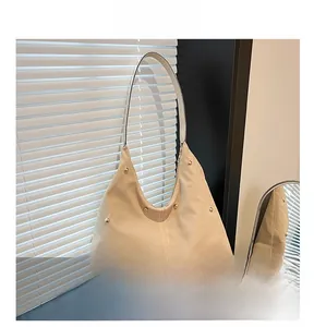 Vue détaillée du grand sac hobo beige avec clous dorés sur matériau en toile grainée
