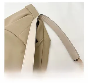 Détail d'un sac à bandoulière en toile kaki avec poignées rondes et sangle large