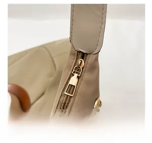 Détail d'une fermeture éclair dorée et d'un renfort en cuir sur un sac fourre-tout
