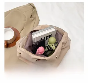 Grand intérieur d'un sac cabas beige contenant tablette, parapluie, téléphone et livres