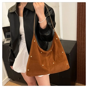 Brown suede hobo bag with gold metal studs shown in a stylish fashion lifestyle setting