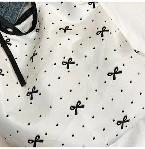 Dettaglio del tessuto stampato con fiocchi neri e pois su una borsa della spesa pieghevole