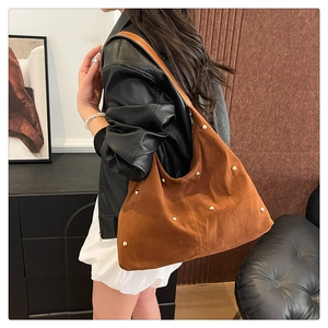 Sac hobo en velours marron avec rivets dorés, vue de profil 3/4 portée par un mannequin