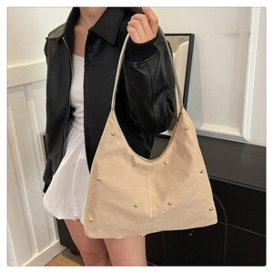 Détail du sac hobo beige avec des rivets dorés et une longue bandoulière de porté