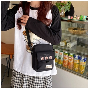 Detail of compact black nylon crossbody bag featuring cute Capybara cartoon print and strap