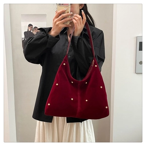 Macro view of burgundy velvet shoulder bag featuring golden hemispherical rivets