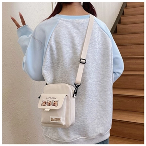 Detail of a beige canvas capybara crossbody bag shown on a model in a minimal setting