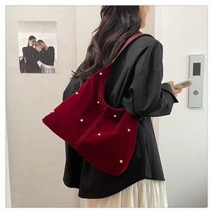 Detail of dark red velvet shoulder bag with gold bead accents on model side view