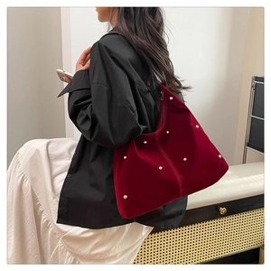 Detailed view of red velvet hobo bag featuring golden metal studs and pleated texture