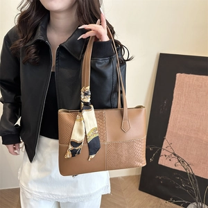 Brown tote bag with snakeskin texture panels and decorative scarf shown on a model