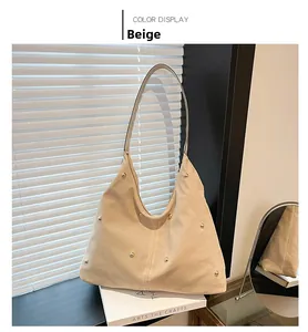 Detail view of beige hobo bag with golden studs placed on white art books
