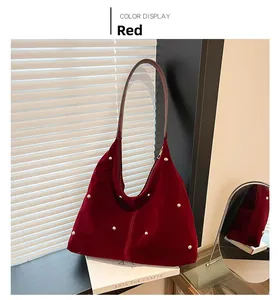 Detailed close-up of dark red suede hobo bag featuring decorative golden metal rivets