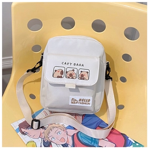 Detail of white canvas crossbody bag featuring Capybara print on a yellow chair
