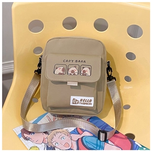 Close-up of khaki canvas crossbody bag with cute capybara print and hello fashion label