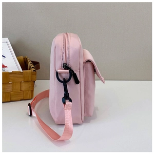 Detailed side view of pink canvas crossbody bag with black zipper and adjustable strap