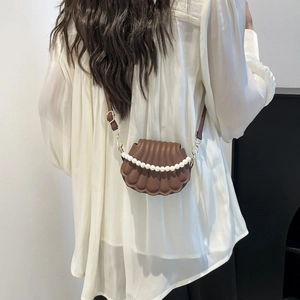 Brown shell-shaped crossbody bag with decorative pearl handle and adjustable strap