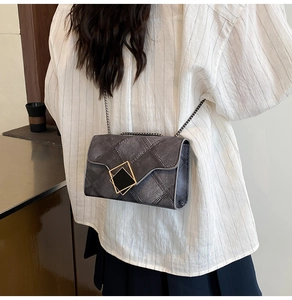 Détail du sac bandoulière gris matelassé avec fermoir carré doré et bandoulière chaîne