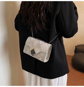 Détail du sac bandoulière matelassé gris clair avec chaîne porté par un mannequin en blazer