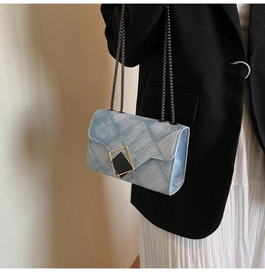 Détail d'un sac à bandoulière en denim bleu clair avec fermoir géométrique et chaîne en métal