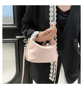 Detail view of pink leather crossbody bag with stitching and gold D-ring buckle