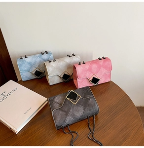 Detail of four colorful gradient quilted flap bags with chain straps on a wooden table