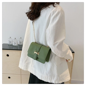 Detail of dark green crocodile texture small crossbody bag with gold H-clasp and chain strap