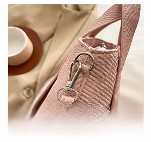 Detail of pink woven tote bag showing silver metal swivel hook and textured strap