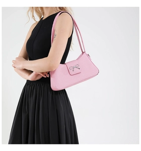 Détail du sac baguette rose tissé avec un nœud métallique argenté sur le rabat